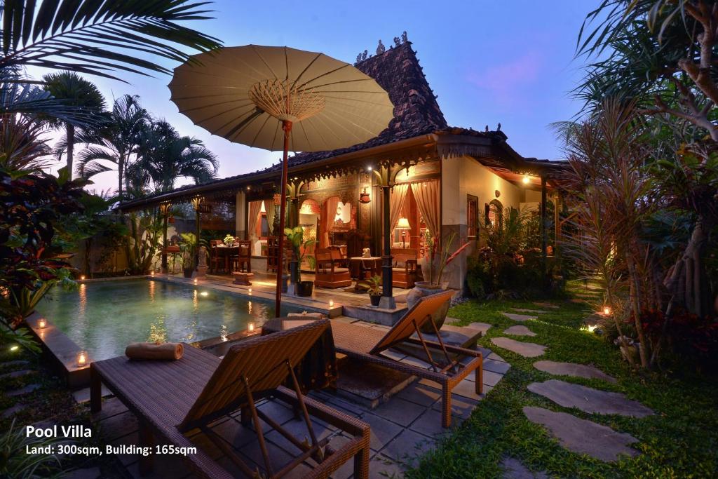 uma casa com uma piscina com uma mesa e um guarda-sol em Ubud Syailendra Heritage Villas by EPS em Ubud