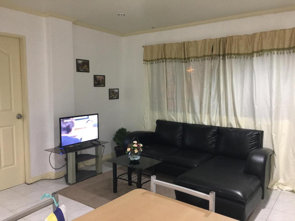 sala de estar con sofá negro y TV en 2bedroom apartment near CONVENTION center, en Iloilo City
