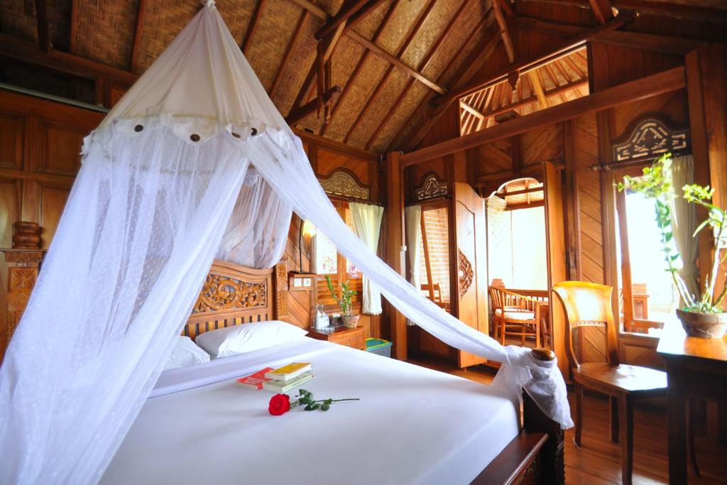 een slaapkamer met een bed met een klamboe bij Puri Lumbung Cottages Restaurant & Spa Munduk in Munduk