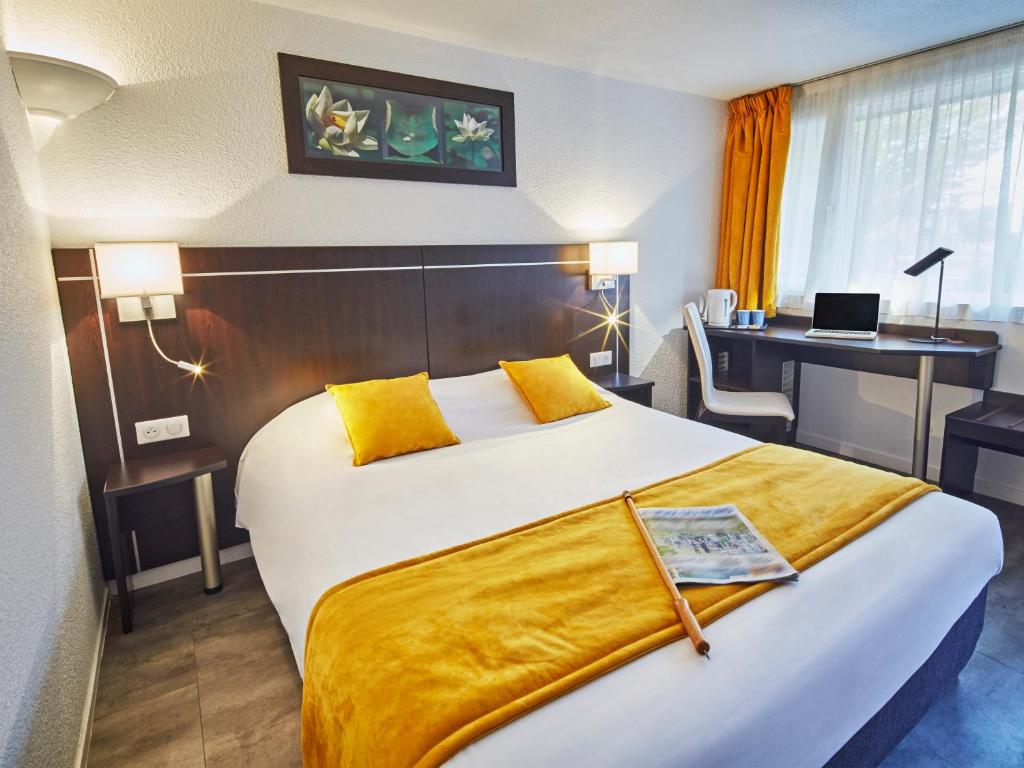 a hotel room with a large bed and a desk at Kyriad Lille Est - Hem in Hem