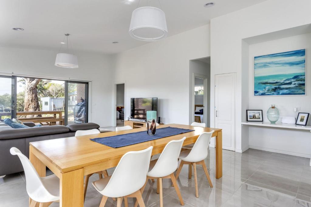 comedor y sala de estar con mesa de madera y sillas blancas en Diamond Bay Beach House: brand new, en Sorrento