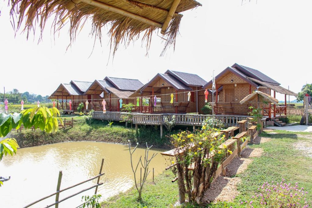 a row of wooden lodges with a pond in front at Chom Chill Nan in Nan