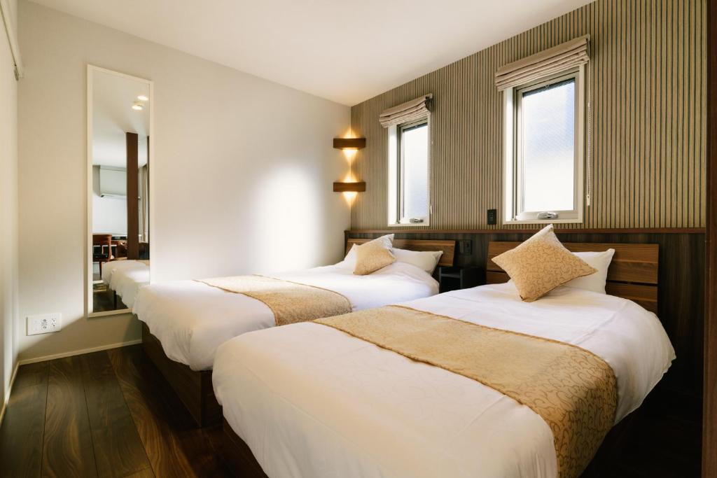 two beds in a room with two windows at GRAND BASE Hakata Haruyoshi in Fukuoka