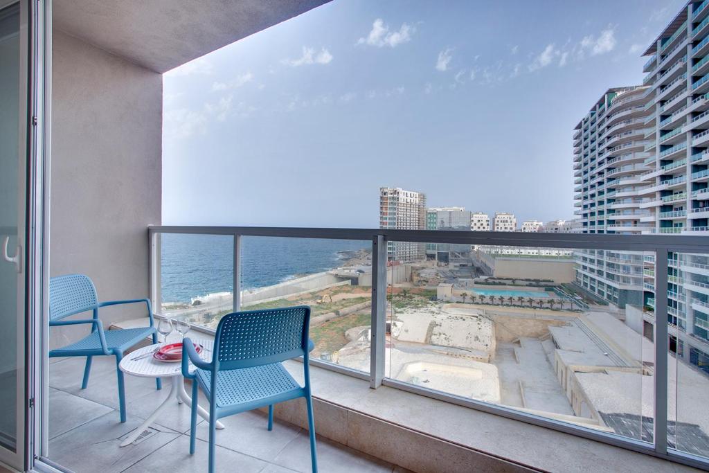 a balcony with chairs and a table and a view of the ocean at Modern Seaview Apartment In a Prime Location in Sliema