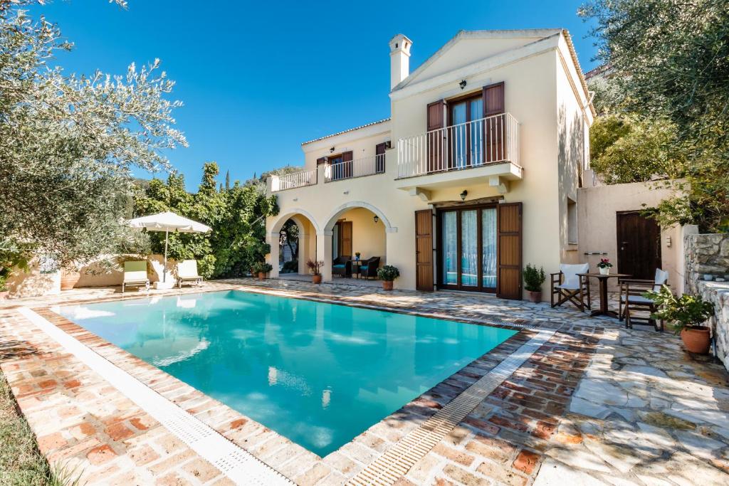 a villa with a swimming pool in front of a house at Mastrogiannis villa Dafne in Kavvadádes
