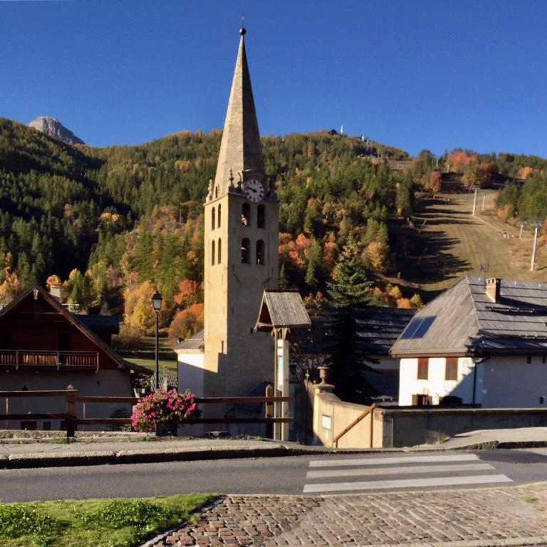 a church with a steeple with a clock on it at Serre Chevalier -Cosy Apartment &quot;Le Coolidge&quot; for 7 down the slopes with stunning view in Saint-Chaffrey