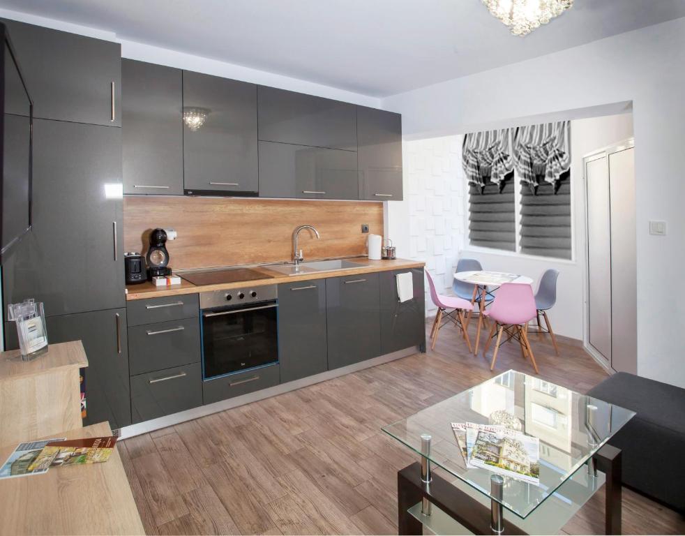 een keuken met grijze kasten en een glazen tafel bij Apartment Diamond CENTER Gabrovo in Gabrovo
