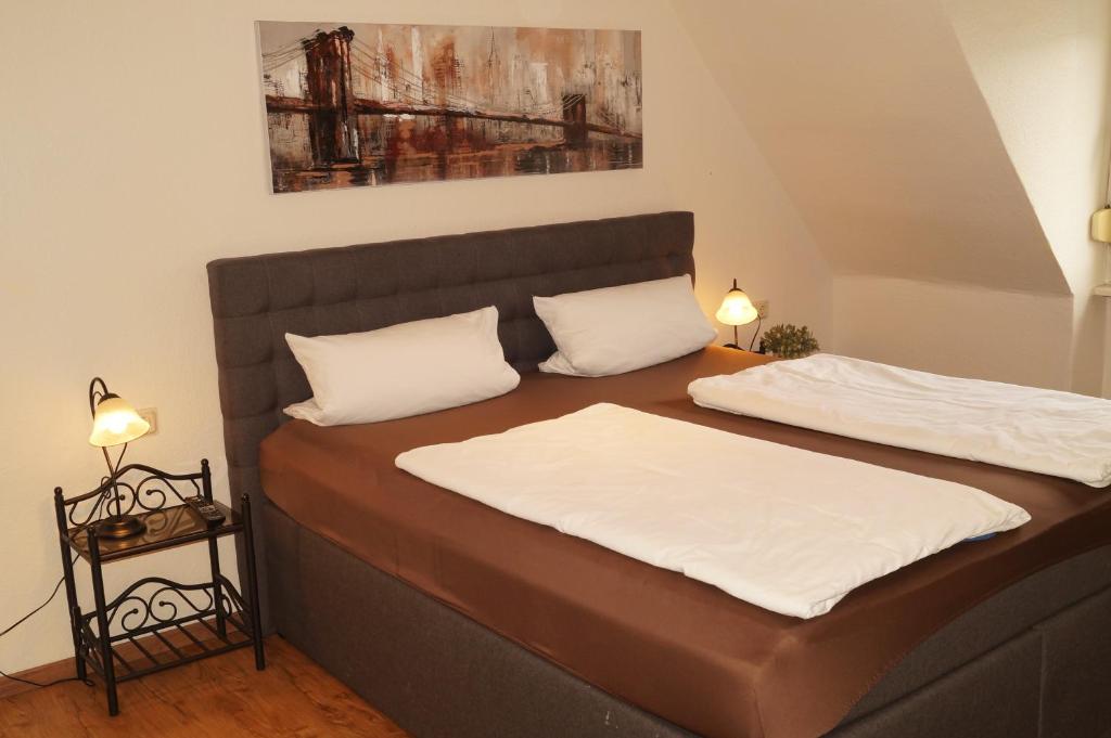 ヴォルムスにあるHotel Boosの白い枕2つが備わる客室内のベッド2台