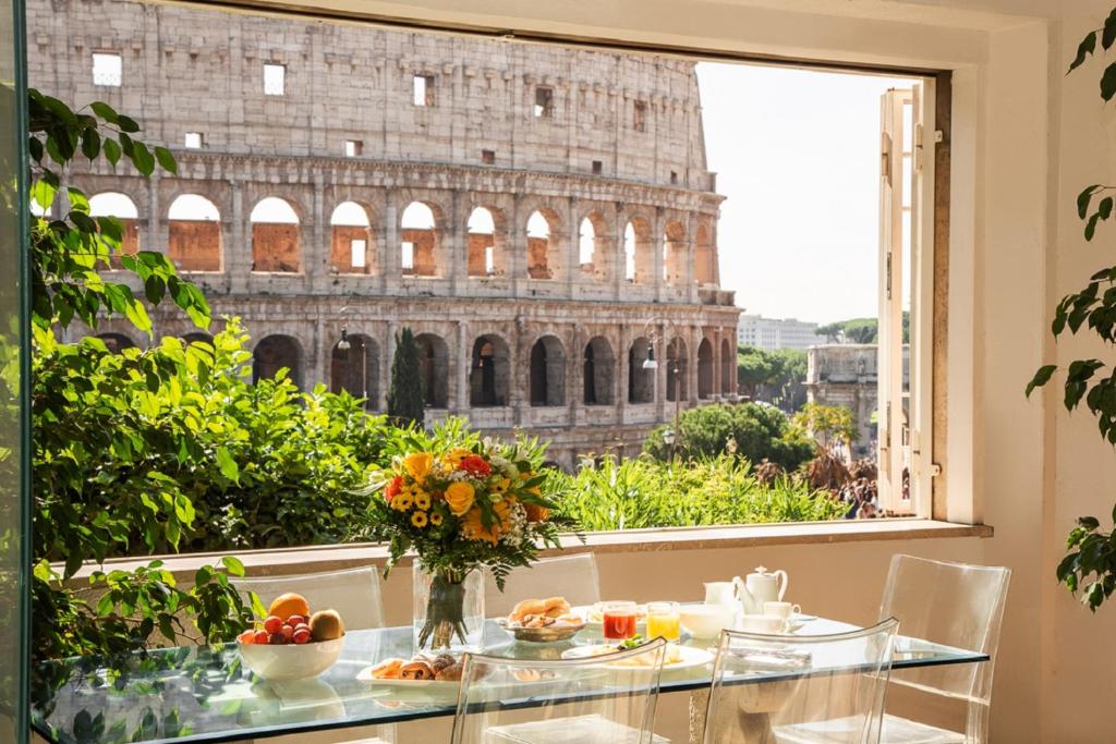 einen Tisch mit Blick auf das Kolosseum aus einem Fenster in der Unterkunft 47Luxury Suites - Colosseo in Rom