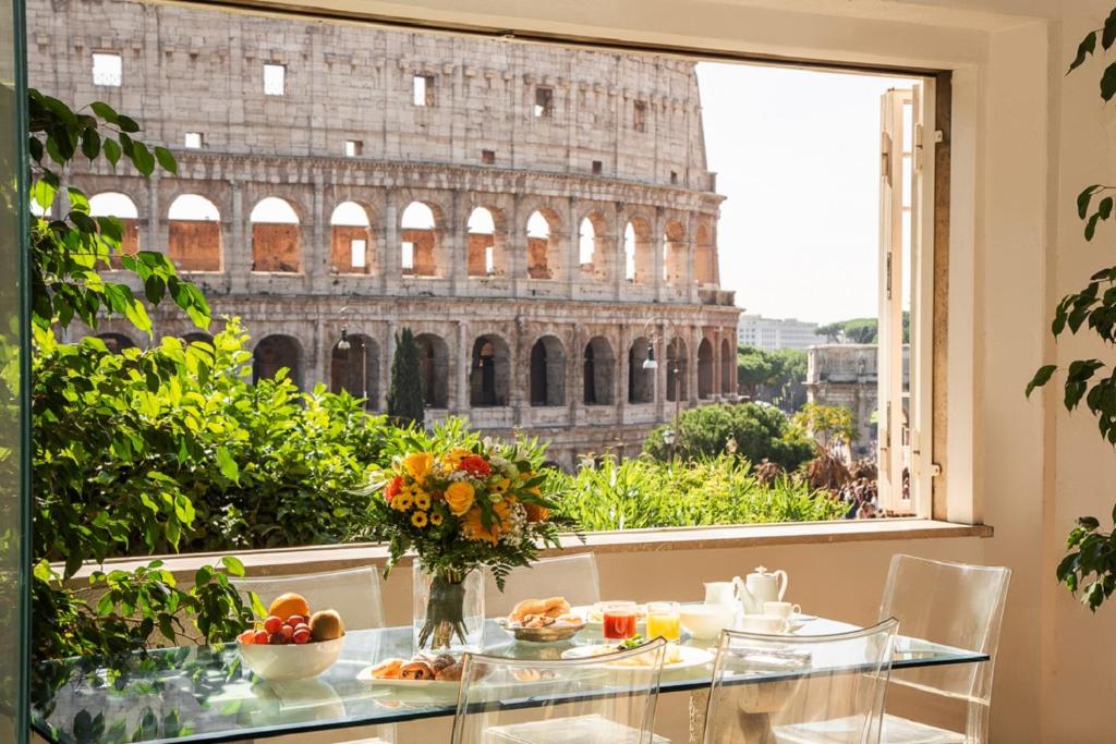 uma mesa com vista para o coliseu a partir de uma janela em 47Luxury Suites - Colosseo em Roma