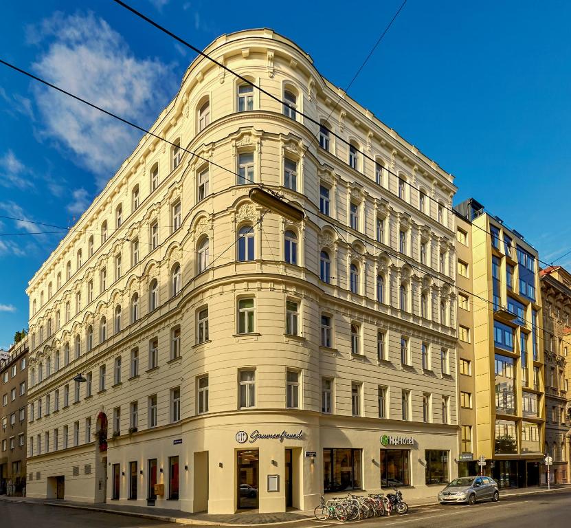 - un grand bâtiment blanc dans une rue de la ville dans l'établissement H+ Hotel Wien, à Vienne