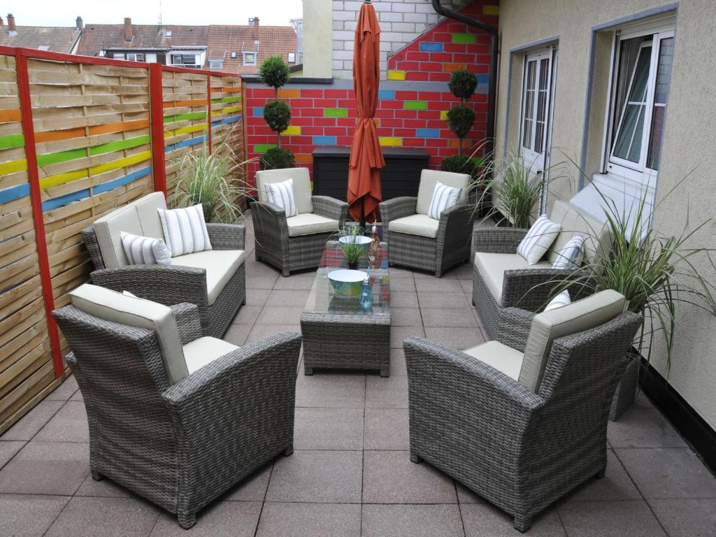 eine Terrasse mit Korbstühlen, Tischen und einem Sonnenschirm in der Unterkunft Ferienwohnung Nickmann im Scheffelhof in Bad Säckingen