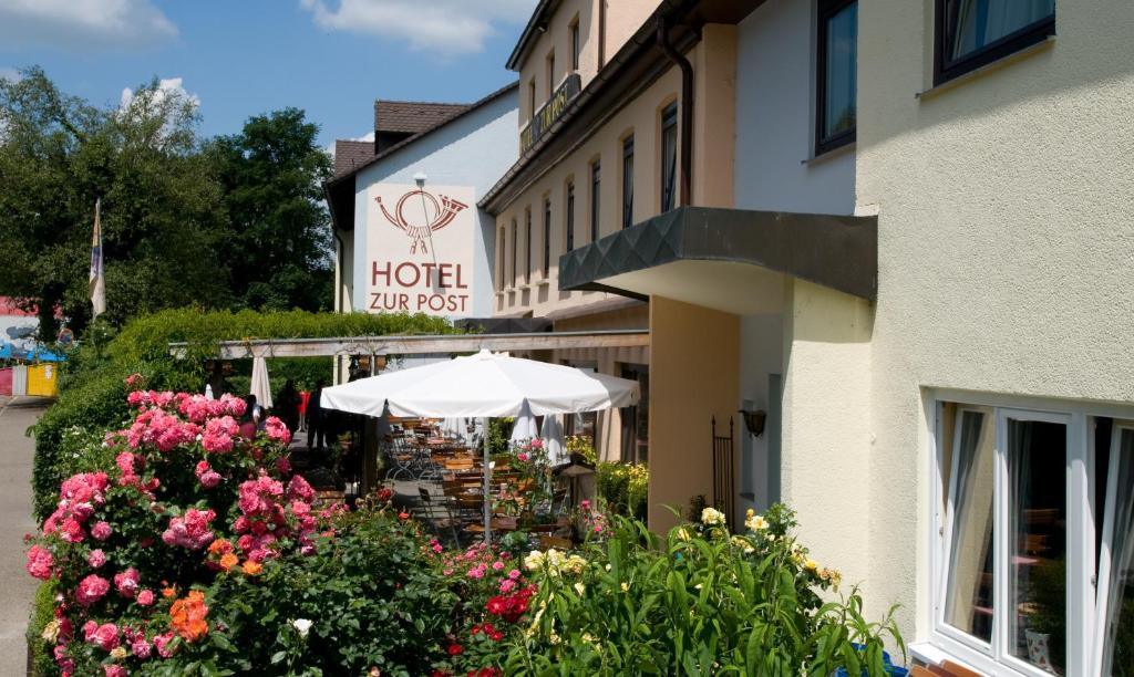 un hôtel avec un parasol et des fleurs devant lui dans l'établissement Hotel zur Post, à Leipheim