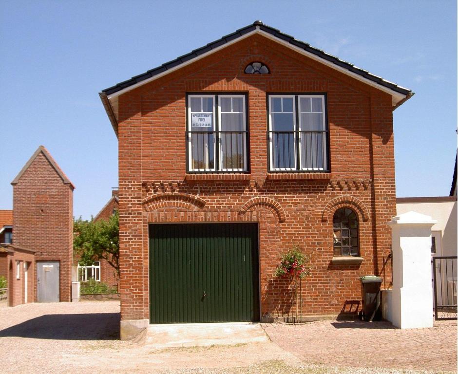 une maison en briques rouges avec un garage vert dans l'établissement Ferienhaus-Utspann, à Lemkenhafen auf Fehmarn