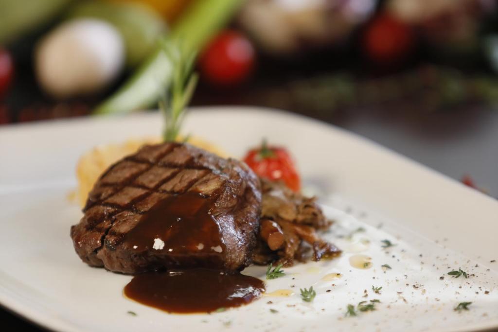 a white plate with a piece of meat with chocolate sauce at ISG Sabiha Gökçen Airport Hotel in Istanbul