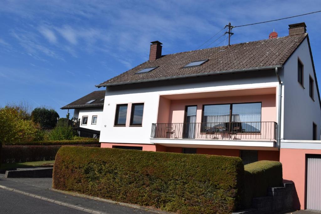 uma casa branca e rosa com uma varanda em Gästehaus Sylvia em Kelberg