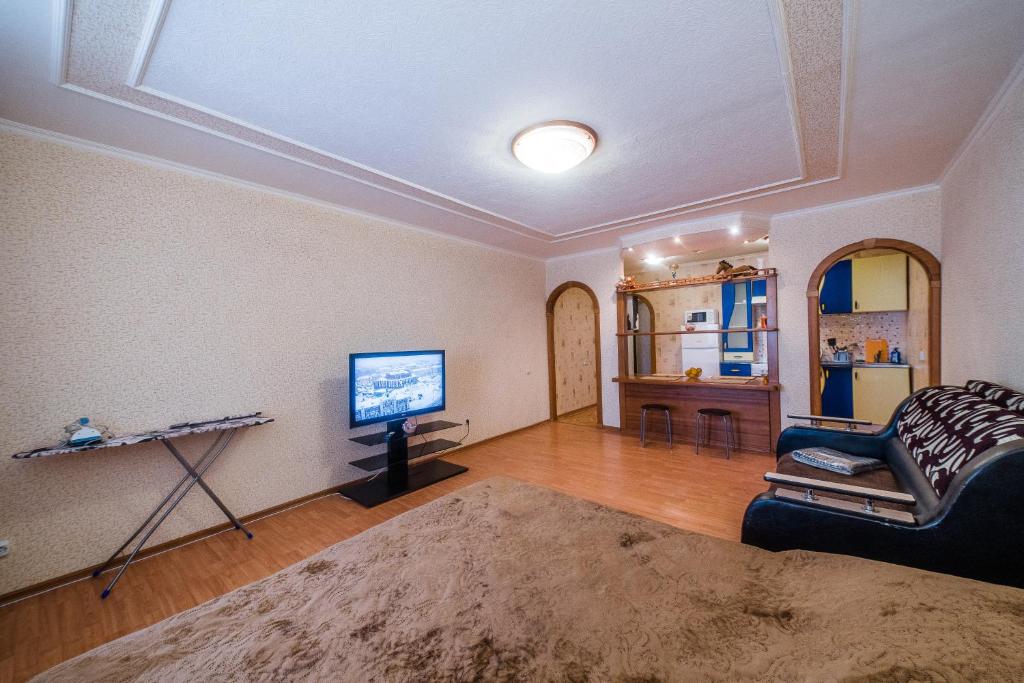 a living room with a couch and a tv on a wall at Большая Подгорная 57 квартира-студия с утепленной лоджией in Tomsk