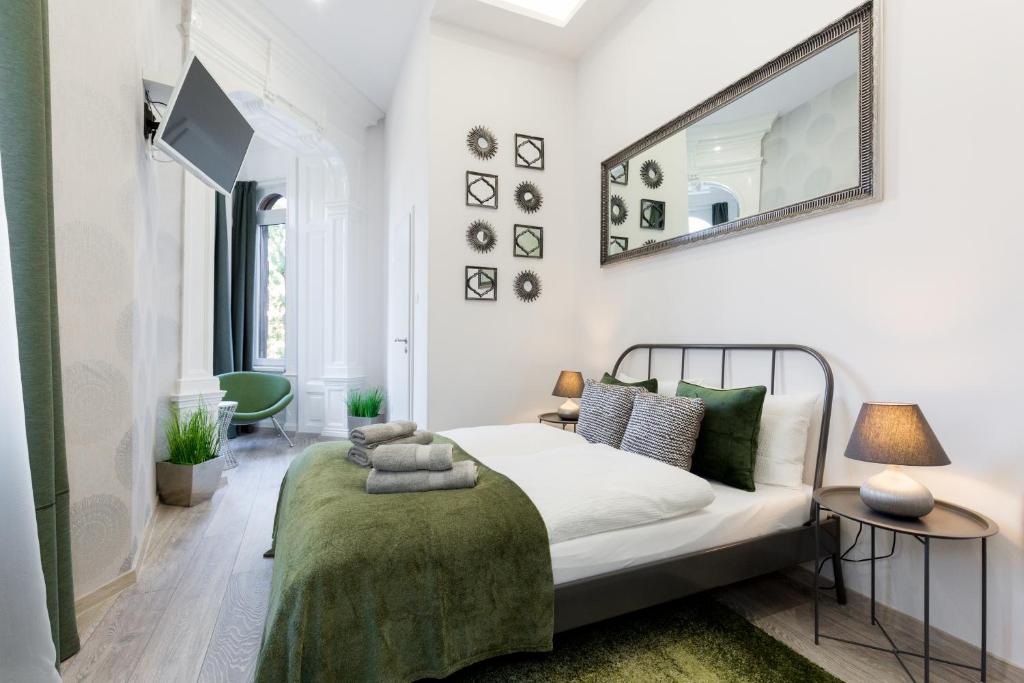 a white bedroom with a bed and a mirror at SB Panzió in Budapest