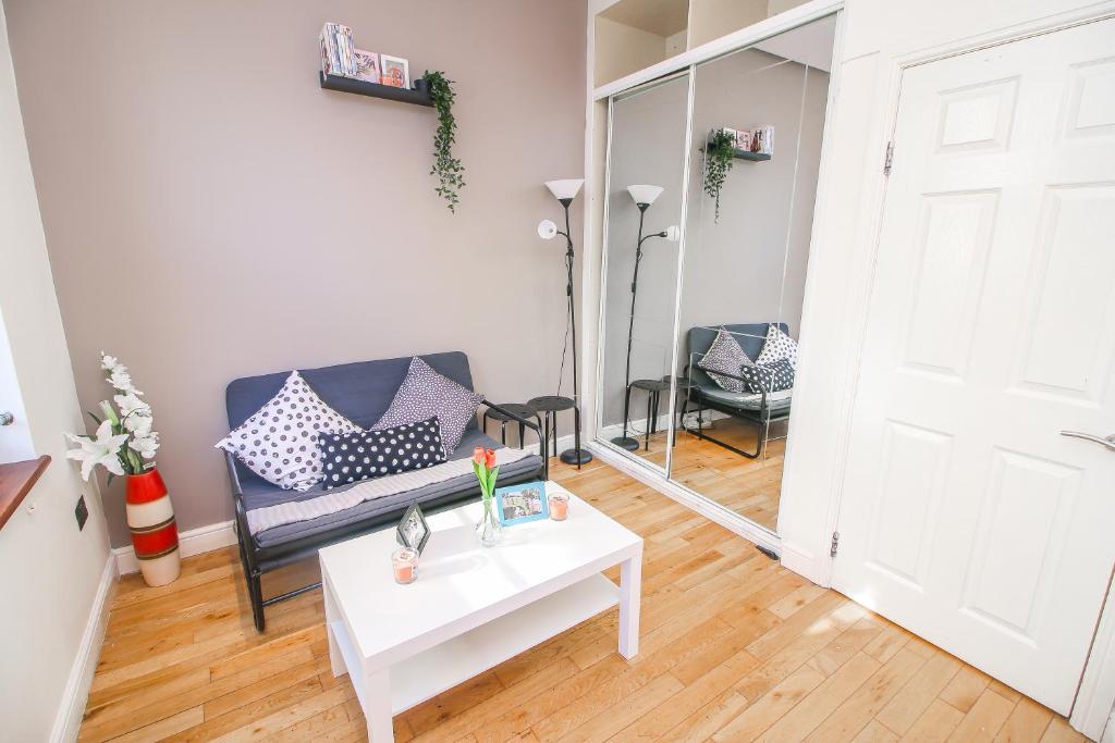 a living room with a couch and a table and a mirror at Studio Flat near Liverpool st & Shoreditch London. in London