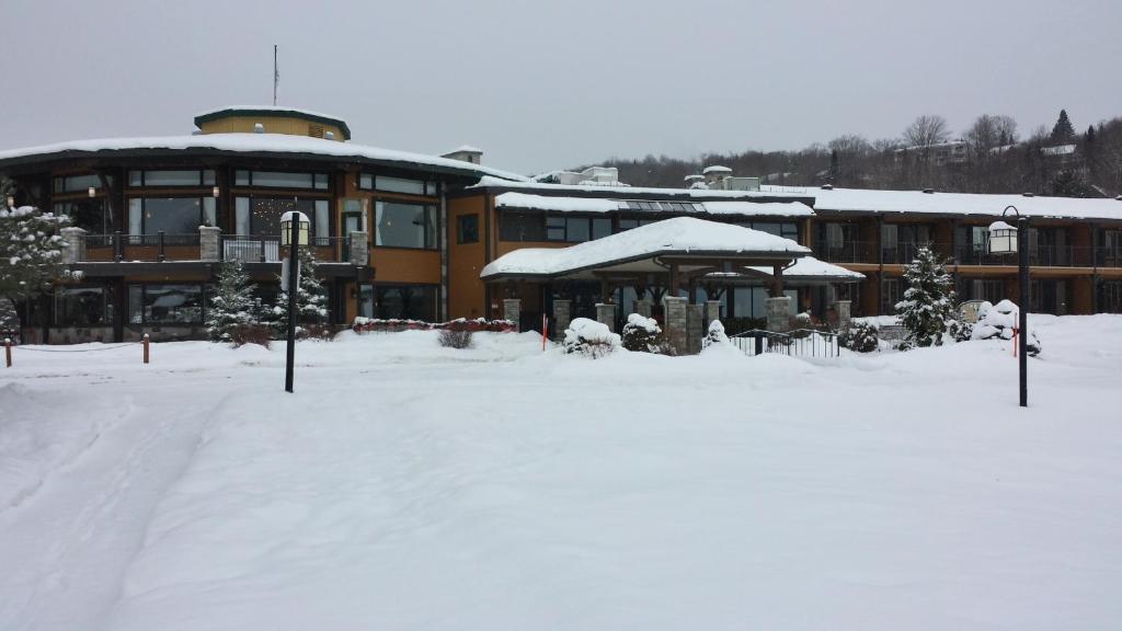 a large building with snow on the ground in front of it at Le Manoir Du Lac DeLage in Stoneham