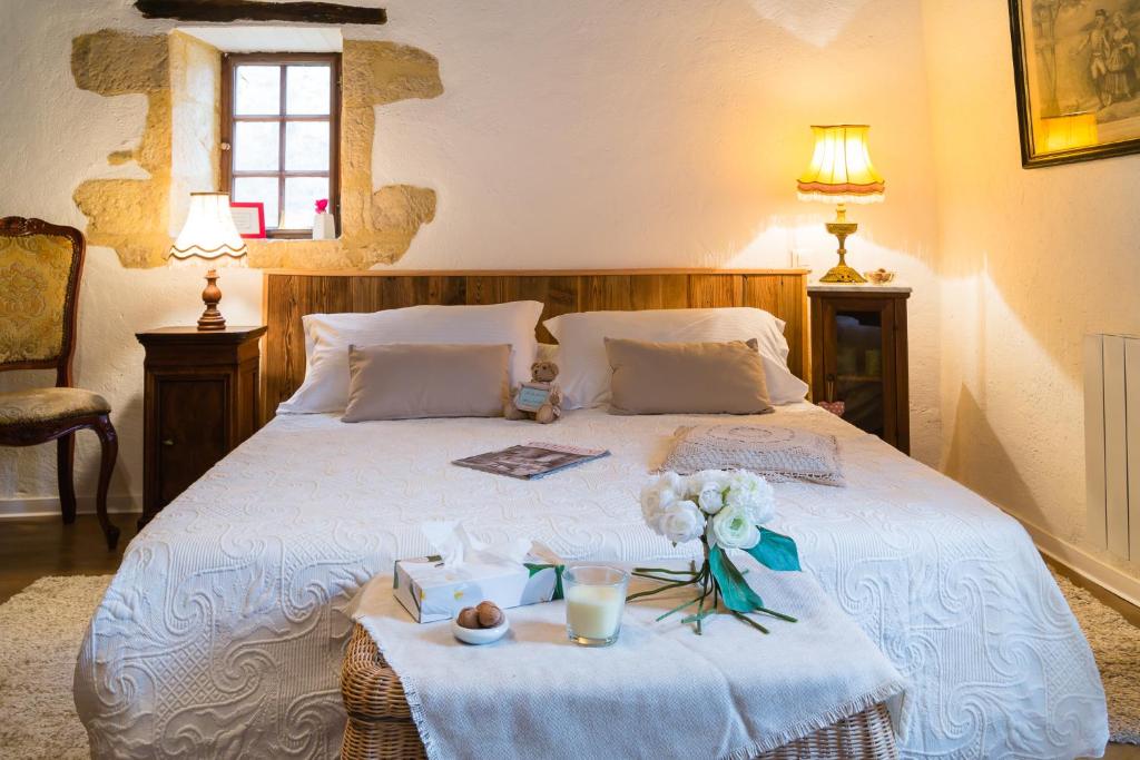 a bedroom with a white bed with flowers on it at Au coeur de Beynac, une maison de caractère avec jardin terrasse in Beynac-et-Cazenac
