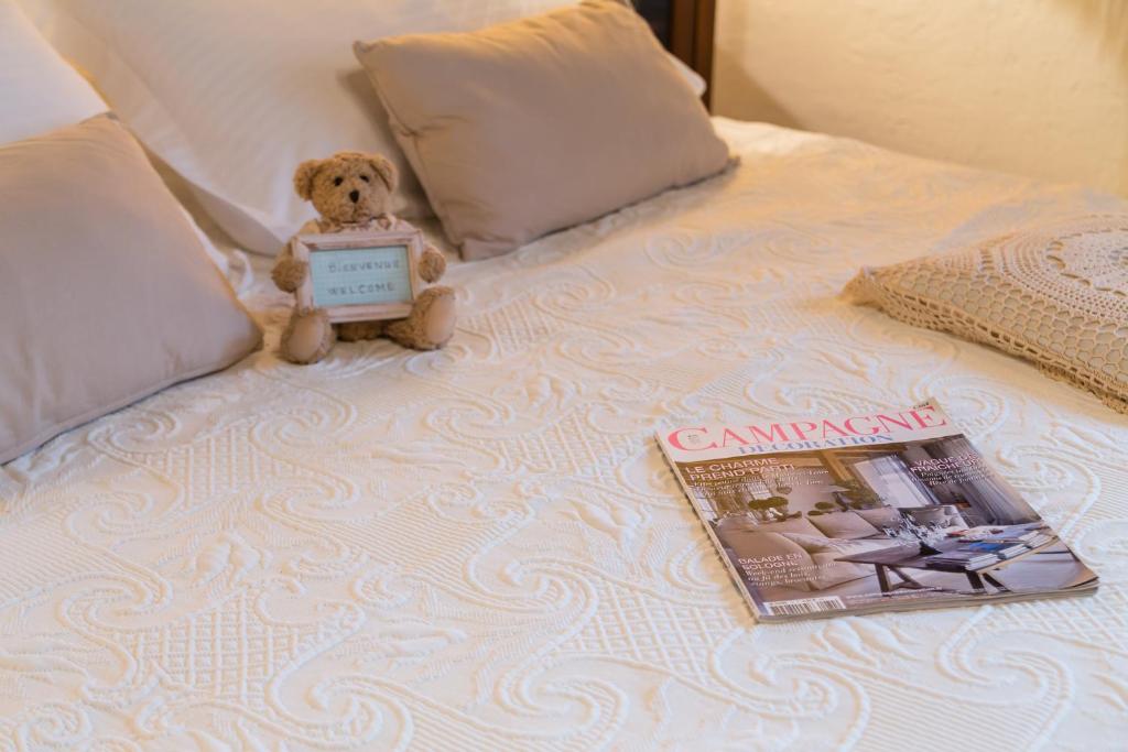a teddy bear sitting on a bed with a magazine at Au coeur de Beynac, une maison de caractère avec jardin terrasse in Beynac-et-Cazenac