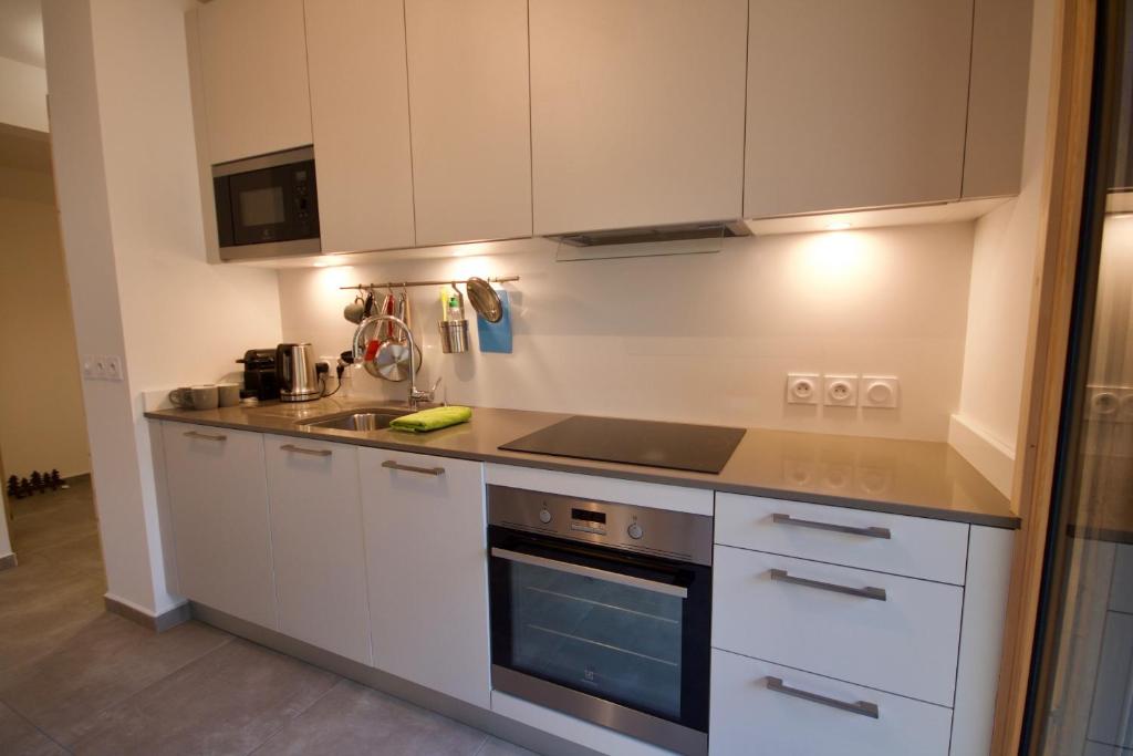 a kitchen with white cabinets and a stove top oven at Django in Les Gets