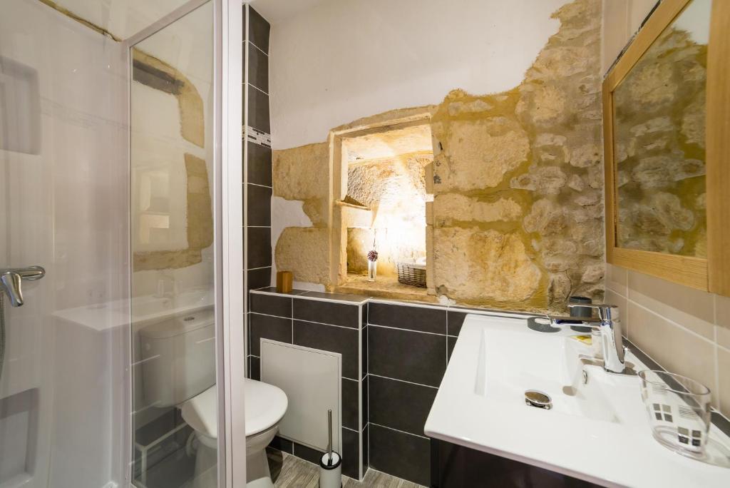 a bathroom with a sink and a toilet and a mirror at Au coeur de Beynac, une maison de caractère avec jardin terrasse in Beynac-et-Cazenac
