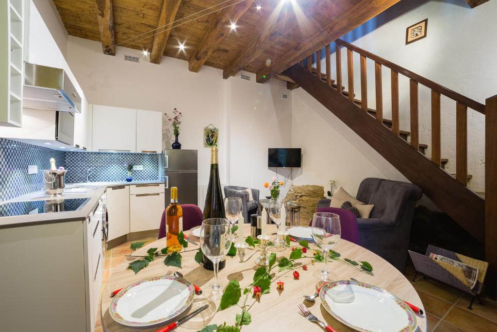 a kitchen and dining room with a table and a staircase at Au coeur de Beynac, une maison de caractère avec jardin terrasse in Beynac-et-Cazenac