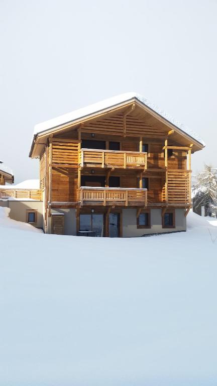 a wooden house with wooden balconies on top of snow at Django in Les Gets
