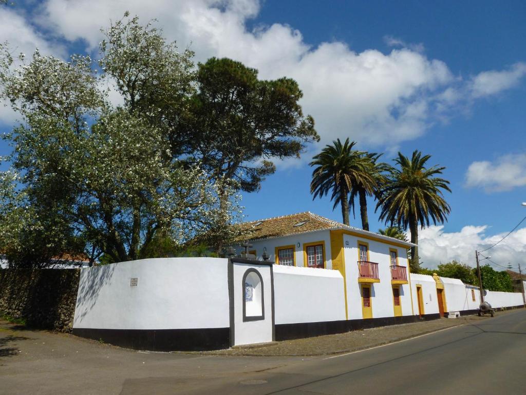 een geel en wit huis met een wit hek bij Quinta do Espírito Santo in Angra do Heroísmo