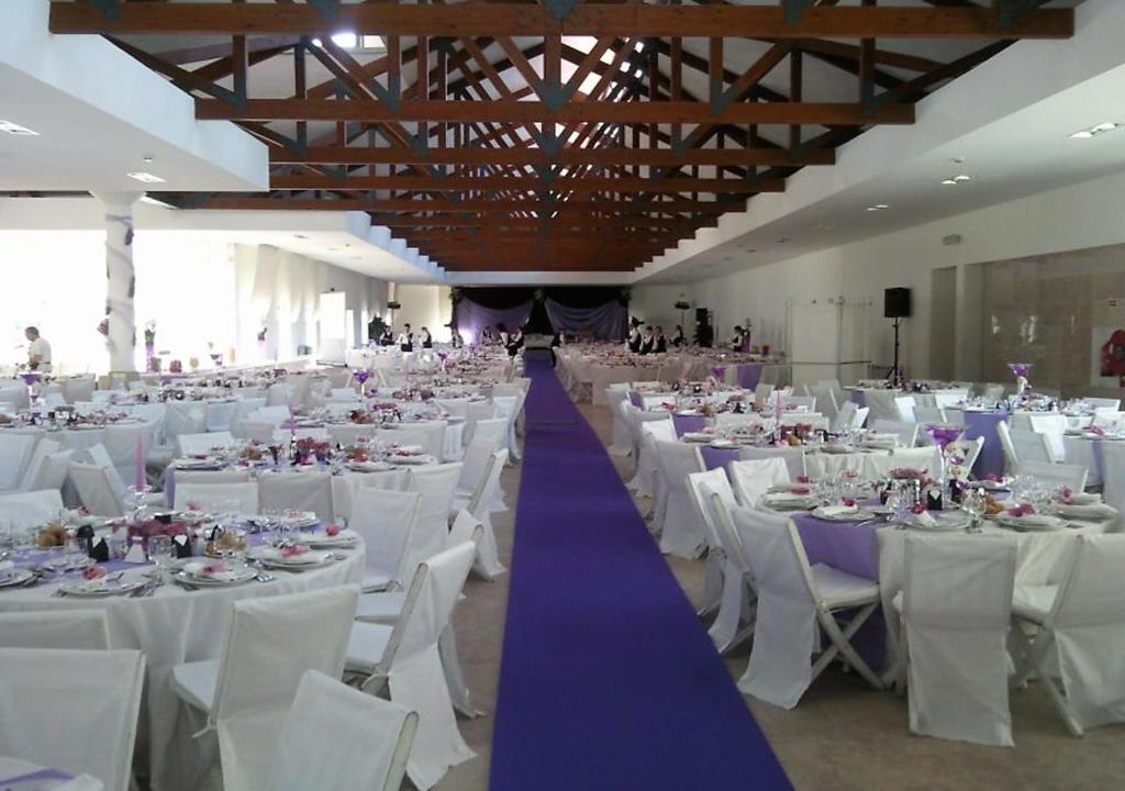 a large banquet hall with white chairs and purple tables at INATEL Caparica in Costa da Caparica