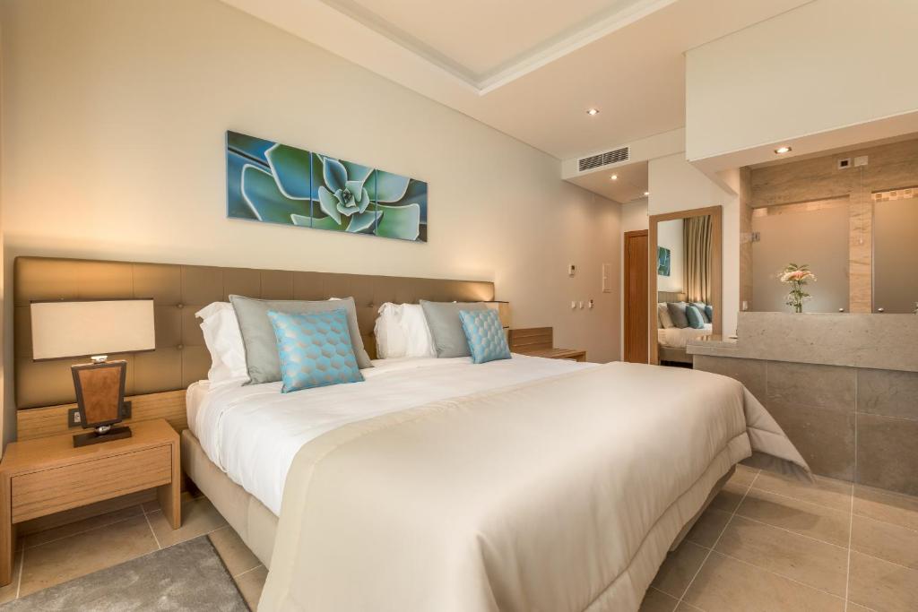 a bedroom with a large white bed with blue pillows at Caneiros Luxury House & Suites in Ferragudo