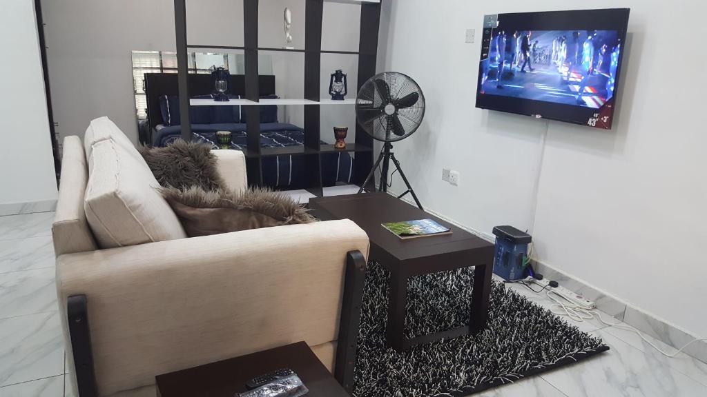 a living room with a couch and a tv at Studio One Bed Apartment - Off Chevron Drive in Lekki