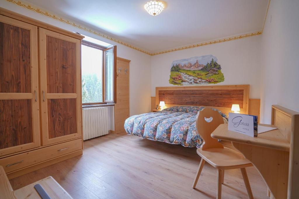 a bedroom with a bed and a desk with a chair at GH Hotel Fratazza in San Martino di Castrozza