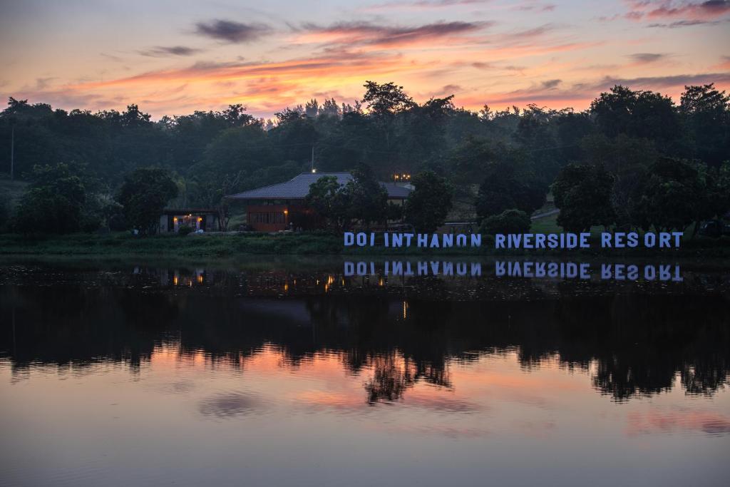 a sign on the side of a lake at sunset at Doi Inthanon Riverside resort in Chom Thong