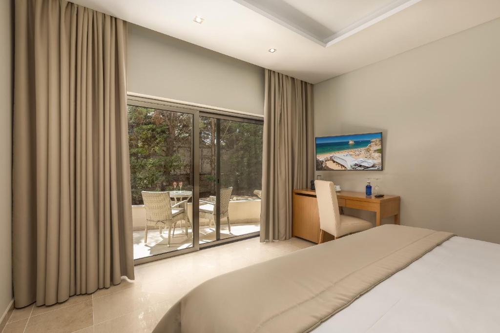 a bedroom with a bed and a desk and a window at Caneiros Luxury House & Suites in Ferragudo