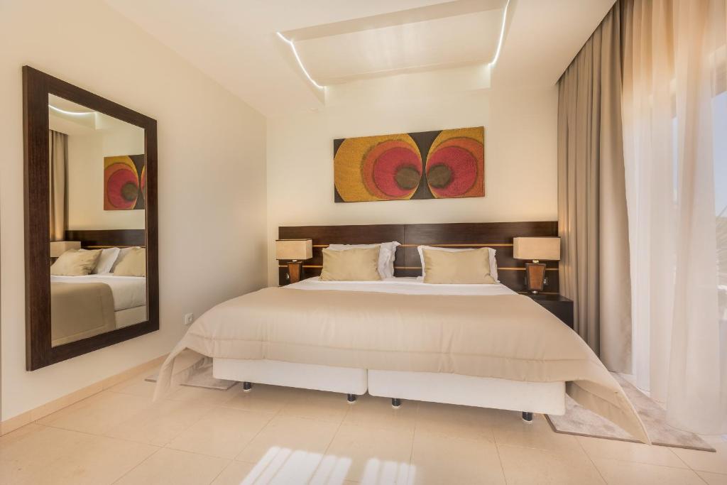 a bedroom with a large bed and a mirror at Caneiros Luxury House & Suites in Ferragudo
