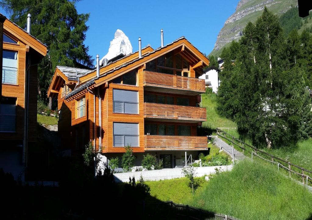 een houten huis op een heuvel met een berg bij Zermatt Appartements in Zermatt