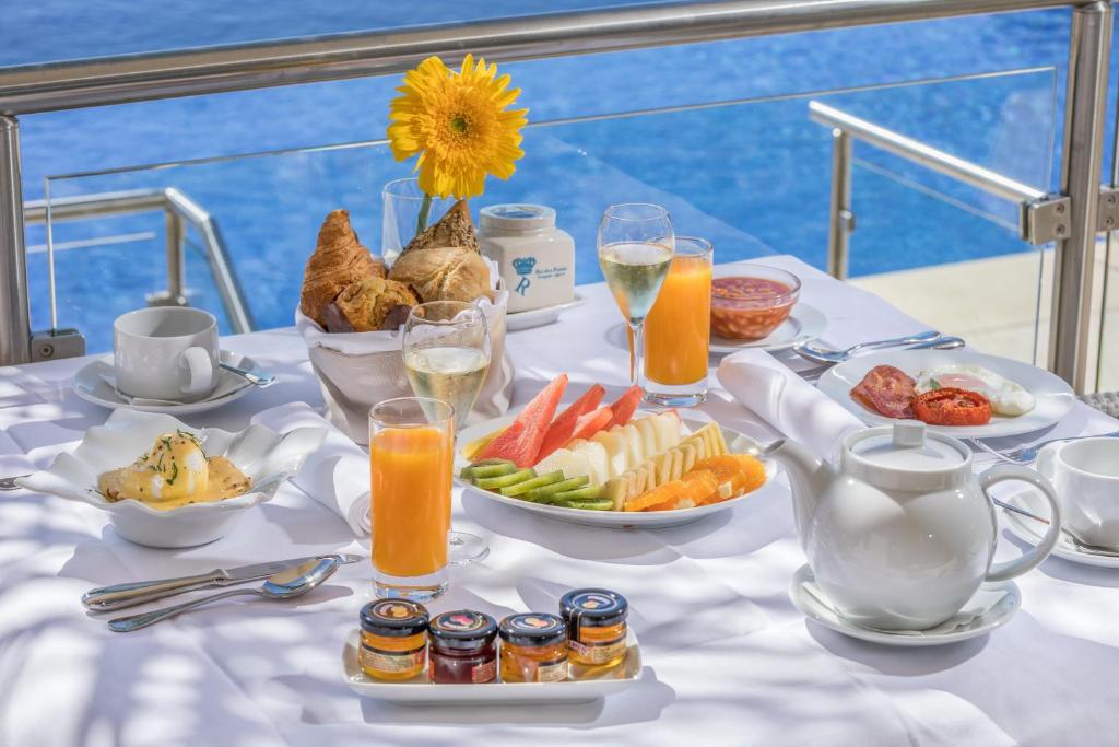 a table with a breakfast of fruit and juice at Caneiros Luxury House & Suites in Ferragudo