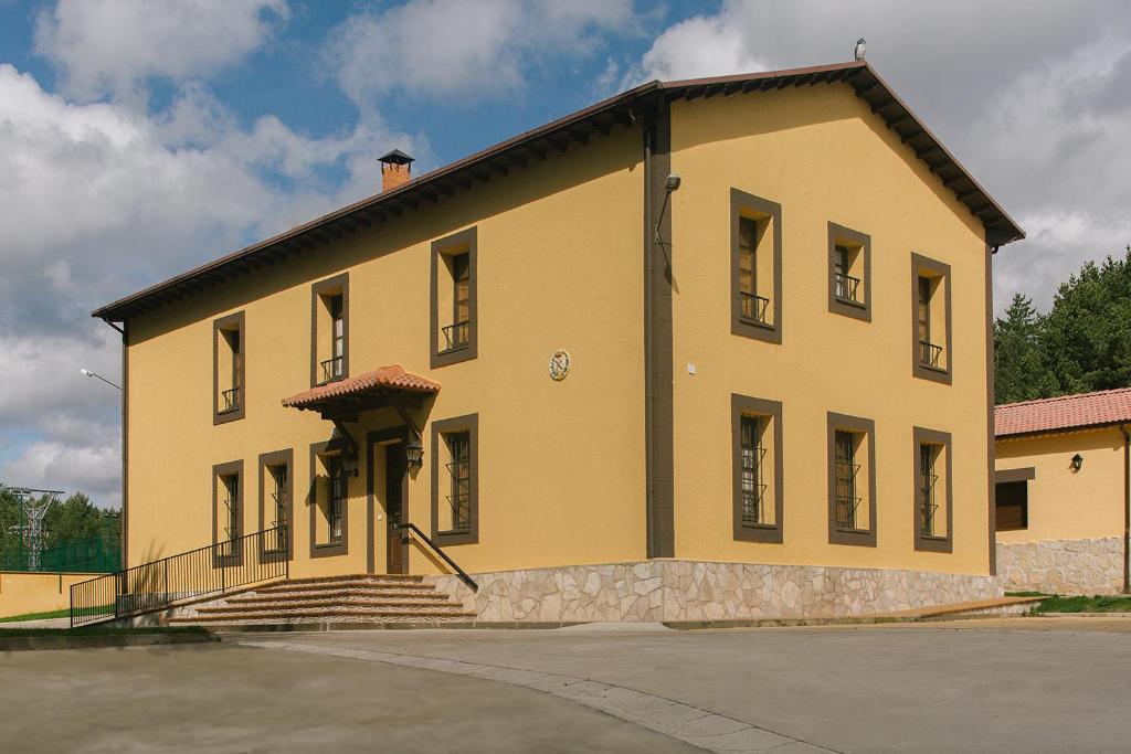 un grand bâtiment jaune avec des escaliers en face de celui-ci dans l'établissement Centro Río Lobos, à Hontoria del Pinar
