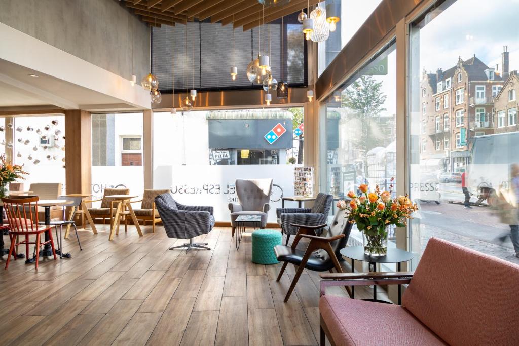 ein Restaurant mit Tischen, Stühlen und Fenstern in der Unterkunft Hotel Espresso in Amsterdam