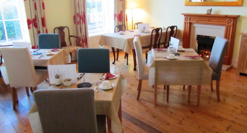 a dining room with tables and chairs and a fireplace at Lammas Park House in Dawlish