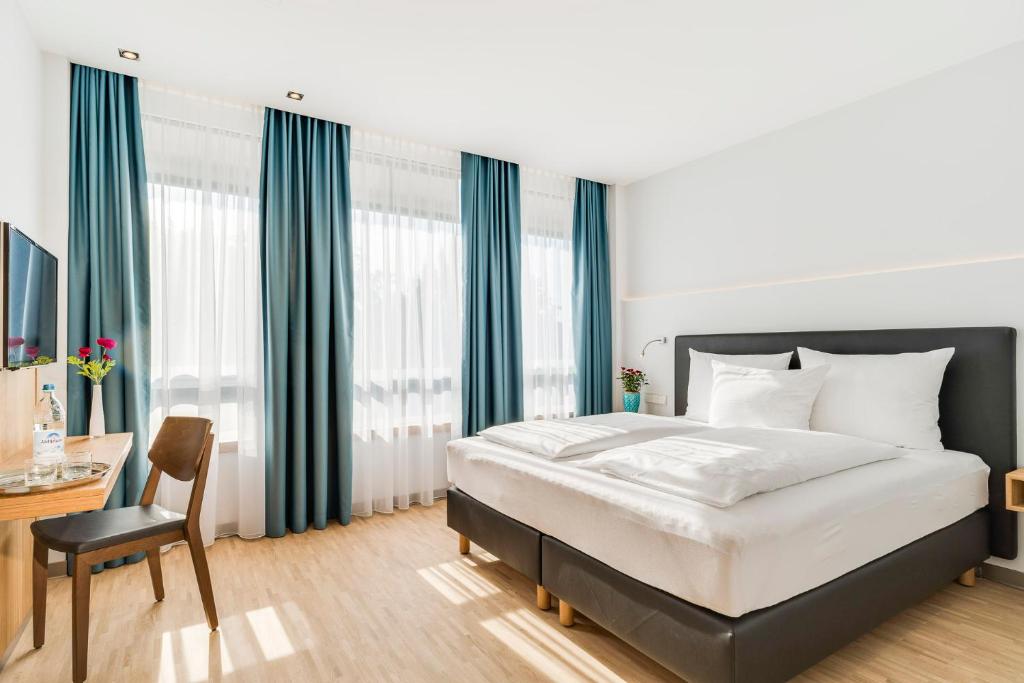 a bedroom with a bed and a desk with a chair at Hotel Apfelrot in Erding