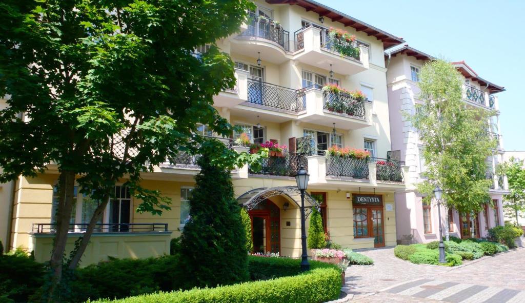 a building with flowers on the balconies and trees at Patio Mare Amber in Sopot