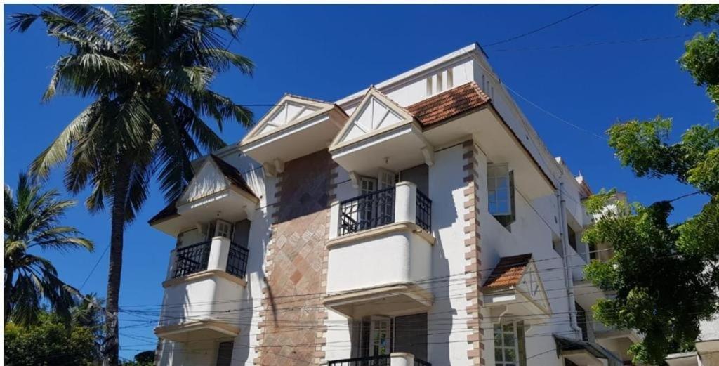 biały budynek z balkonem i palmą w obiekcie ROYALE ACHAYA w mieście Ćennaj