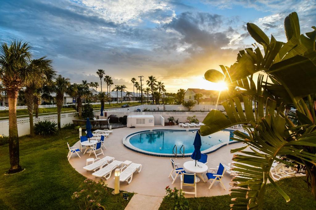 a resort pool with lounge chairs and the sunset at Daytona Beach Shores Condos in Daytona Beach Shores
