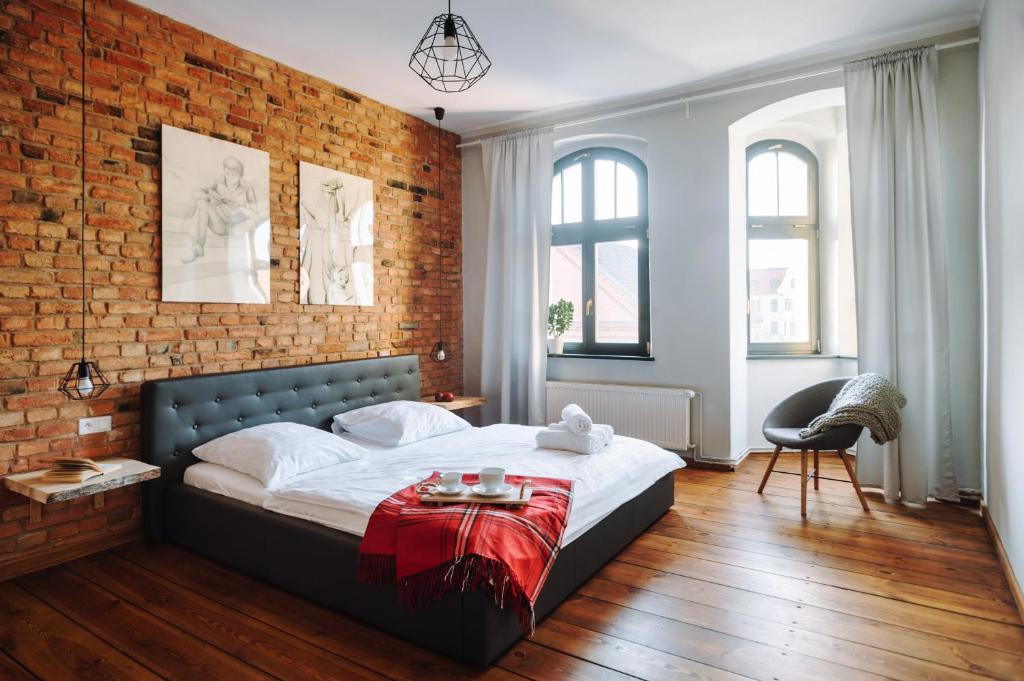 a bedroom with a large bed with a brick wall at Apartamenty Europa in Toruń