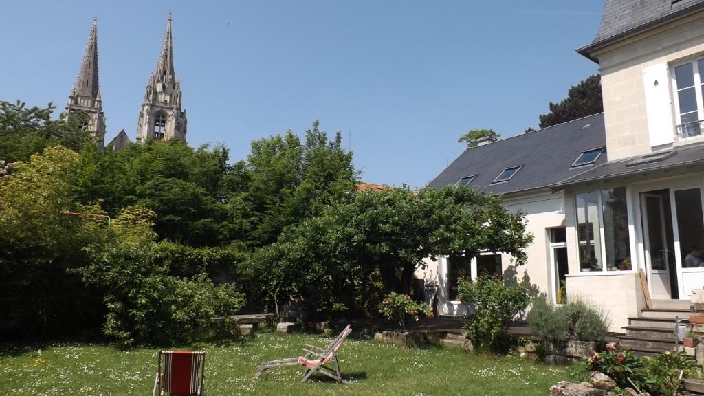 una casa y una iglesia con un campanario en el fondo en Au coeur de soissons 1 en Soissons