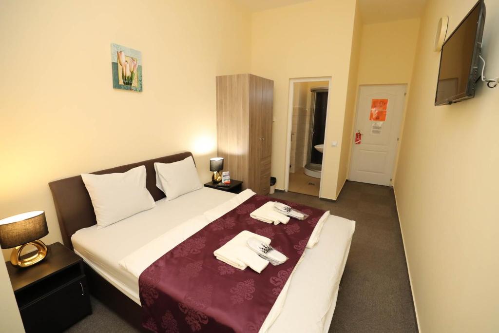ein Hotelzimmer mit einem Bett mit zwei Handtüchern darauf in der Unterkunft Hotel California in Budapest